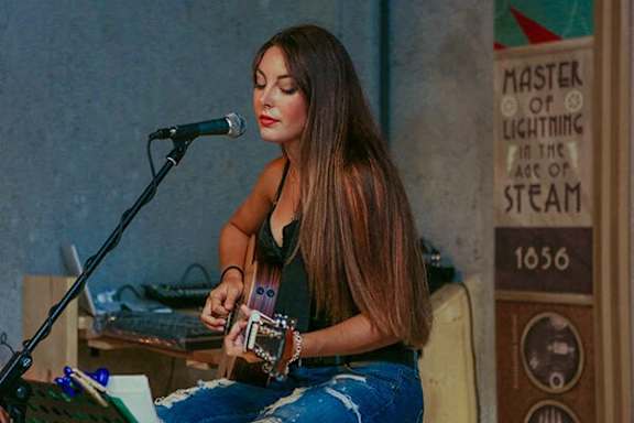 A woman playing a guitar in front of a microphone.