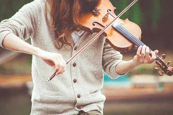 A woman playing the violin outdoors.