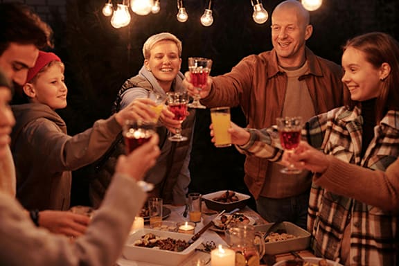 A group of people toasting with drinks at a dinner party.
