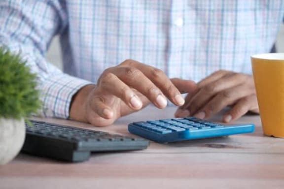 a man sitting at a desk using a calculator and a computer keyboard
