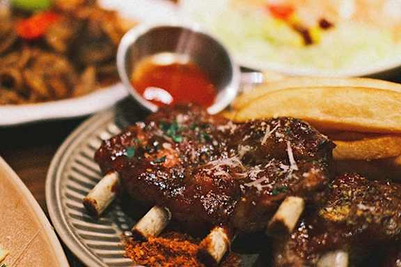 A plate of barbecued ribs with a side of fries and salad.