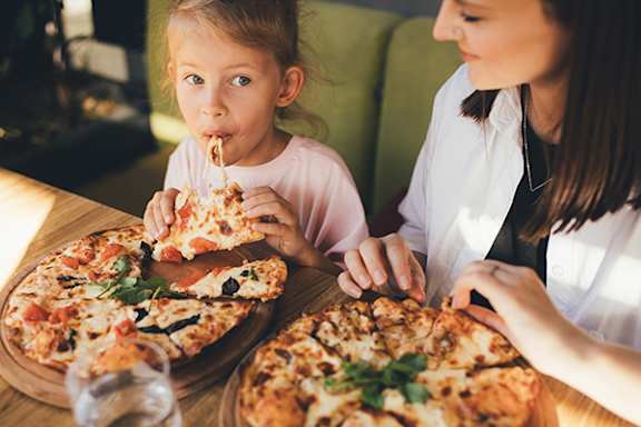 A woman and a girl are eating pizza together.