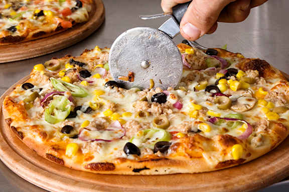 A person is cutting a pizza with a pizza cutter.