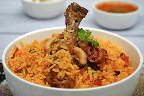 A bowl of rice with meat and nuts.