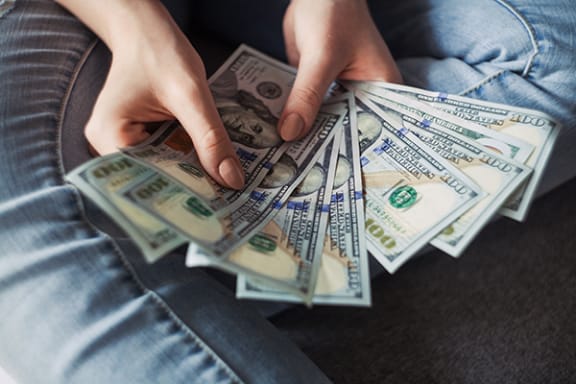 a person sitting on a couch holding a bunch of money