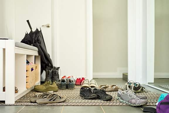 A collection of shoes are lined up on a rug in a hallway.