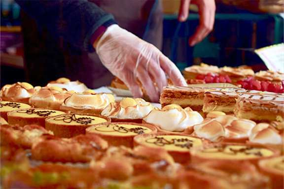 A person in a white glove is reaching for a piece of cake.