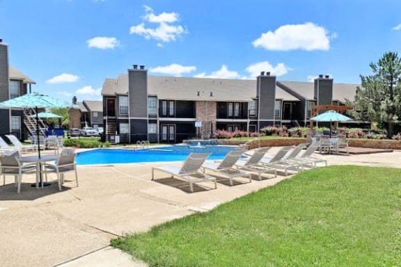 a swimming pool with chairs and umbrellas in front of a building
