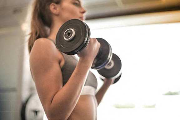 A woman lifting a dumbbell in a gym.