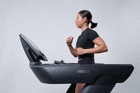 A woman is running on a treadmill with a screen and the number 4502 on it.