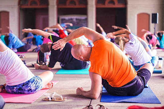 A group of people practicing yoga in a row.
