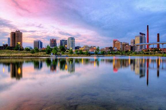 A city skyline is reflected in a body of water.