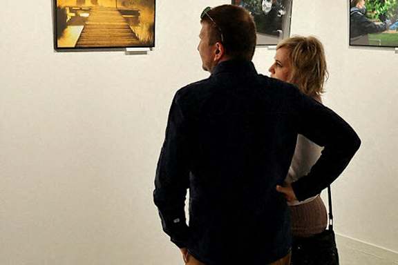 A man and a woman are looking at paintings in an art gallery.