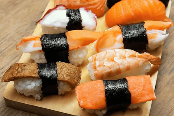 A wooden board with sushi rolls on it.