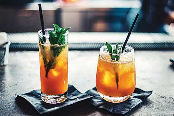 Two glasses of iced tea with mint leaves on top.