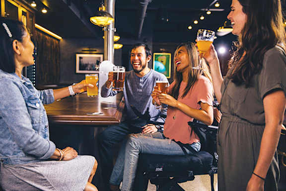 A group of people are toasting with drinks in a bar.