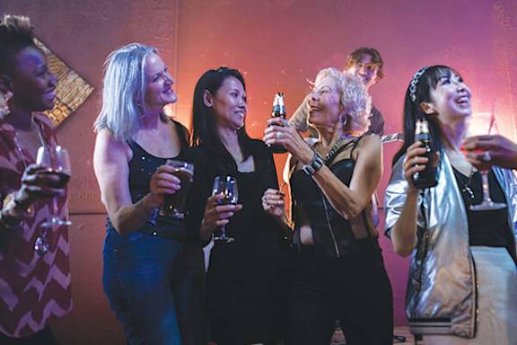 A group of people are standing together holding drinks.