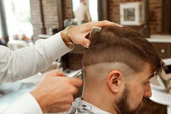 A man getting a haircut with a barber using a comb and scissors.