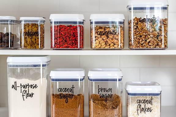 A shelf with containers of ingredients such as flour, sugar, and nuts.