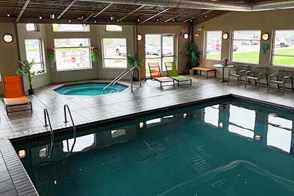 A large indoor swimming pool with a glass wall and a bench area.