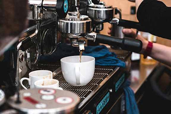 A person is making a cup of coffee using a coffee machine.