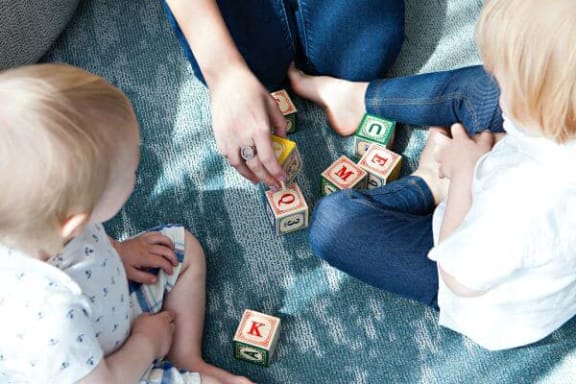 a mother and two children playing with blocks on the floor