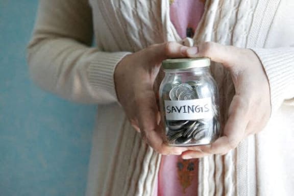 a woman holding a jar with money in it