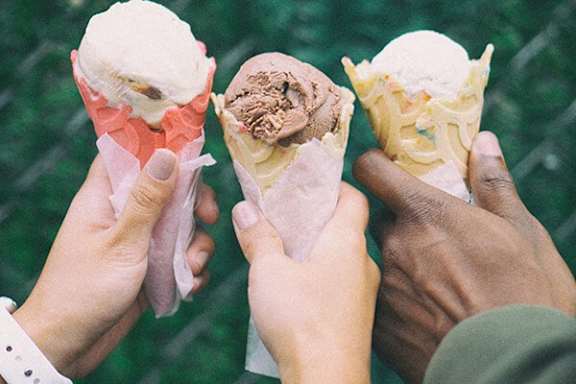 Three people holding ice cream cones with different flavors.