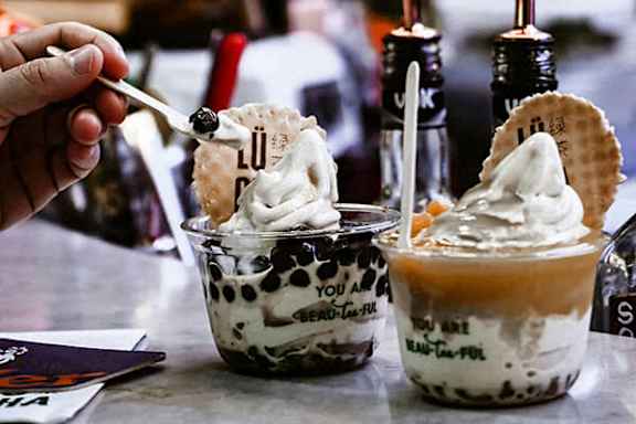 A person is eating a dessert with whipped cream and cookies.