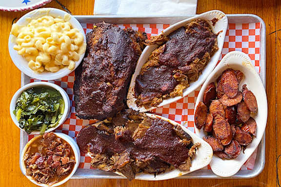 A tray of food including meat and macaroni and cheese.