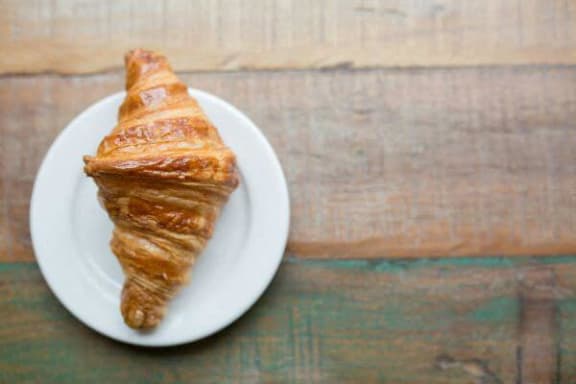 a croissant on a white plate on a table