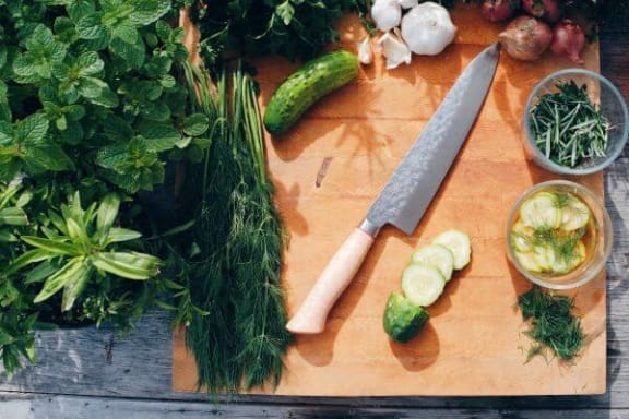a cutting board with vegetables and a knife on it