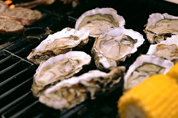 Oysters on the grill with a yellow object in the foreground.