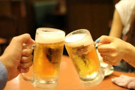 two people are holding up glasses of beer