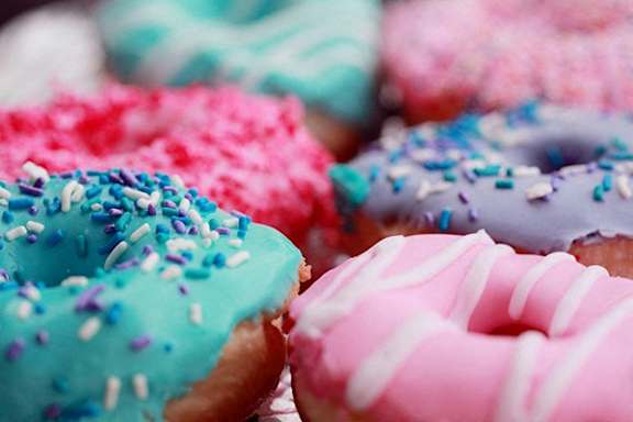 A close up of assorted donuts with sprinkles and icing.