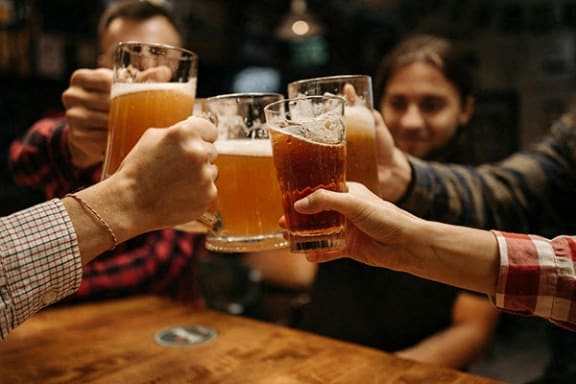 a group of people holding up glasses of beer