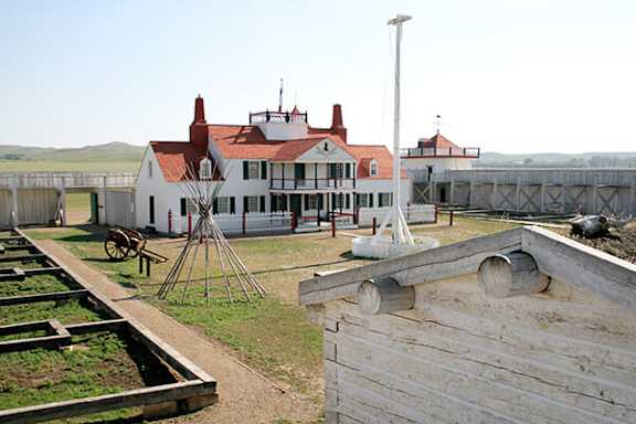 A white house with a red roof and a wooden fence.