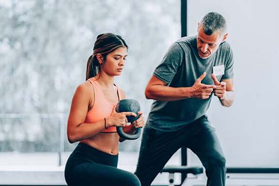 A man and a woman are exercising together in a gym.