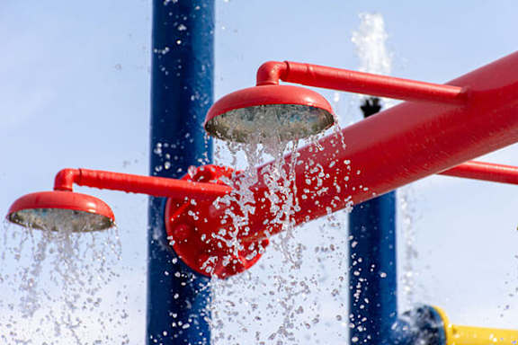 Water is spraying out of a red shower head.