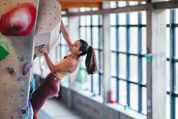 A woman climbing a rock wall indoors.