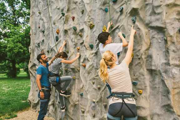 Three people climbing a rock wall outdoors.