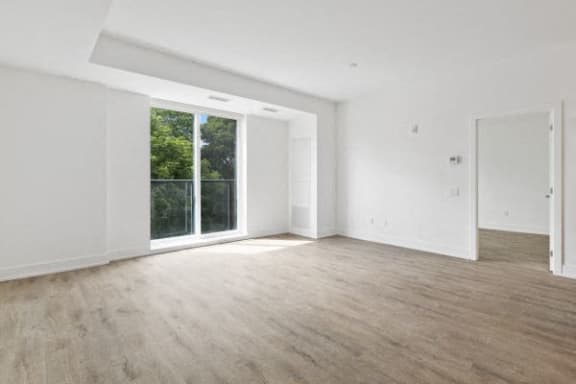 an empty living room with white walls and a large window