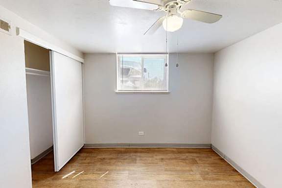 A room with a ceiling fan and a window.