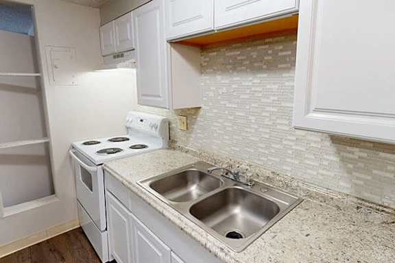 A white kitchen with a stove and sink.