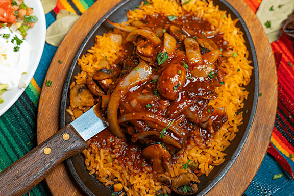 A dish of rice topped with mushrooms and a brown sauce.