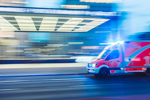 An ambulance is in motion on a city street.