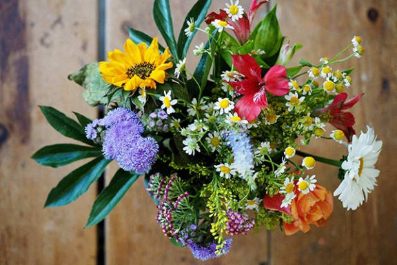 a bouquet of colorful flowers in a vase on a wooden table