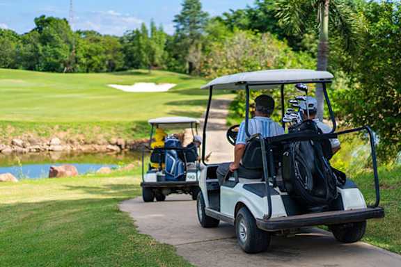 Two golf carts with golfers inside driving on a path.
