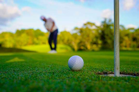 A golfer is about to hit a golf ball out of a hole.