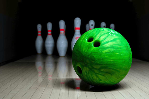 a green bowling ball in front of a row of bowling pins